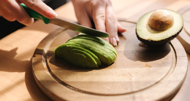 person slicing an avocado