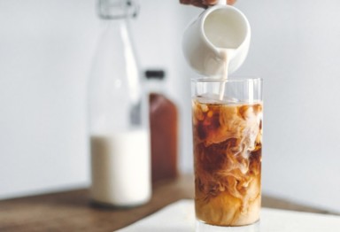 Milk being poured into glass of cold brew coffee