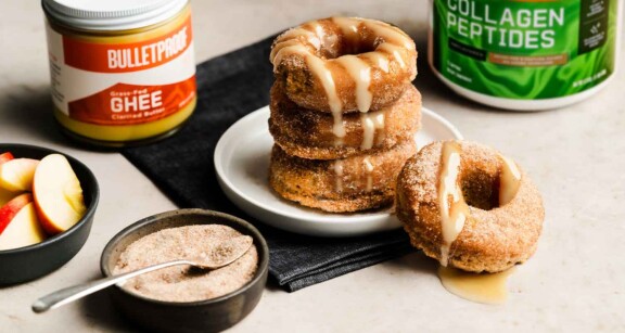 Stack of apple cider donuts with Bulletproof Grass-Fed Ghee and Bulletproof Unflavored Collagen Peptides in the background.