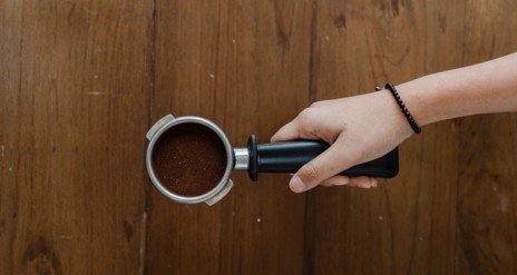 Hand hält Siebträger mit Espresso Kaffee