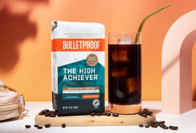 Glass of iced coffee siting next to a bag of Bulletproof The High Achiever coffee