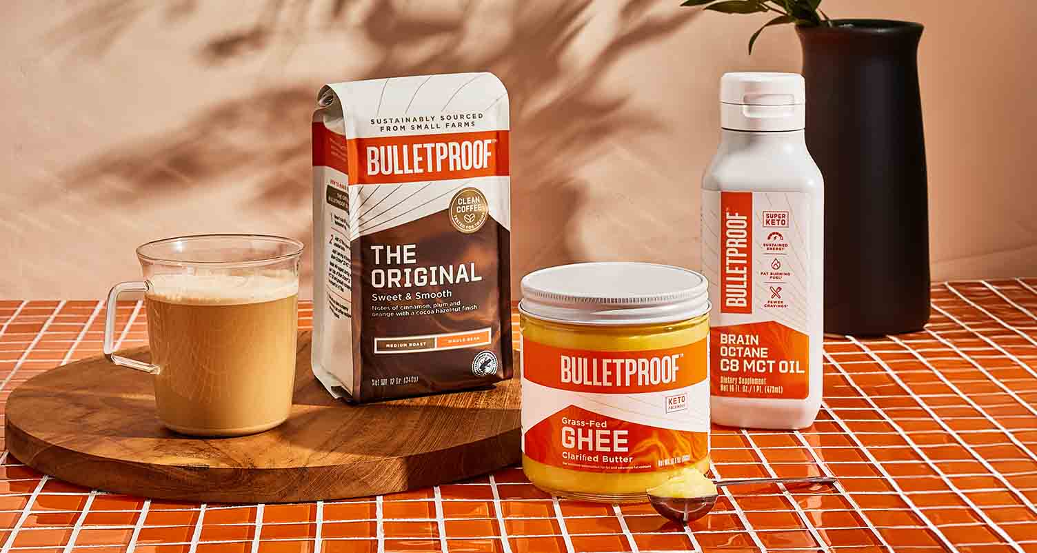 Bulletproof products on an orange counter with a mug of coffee.