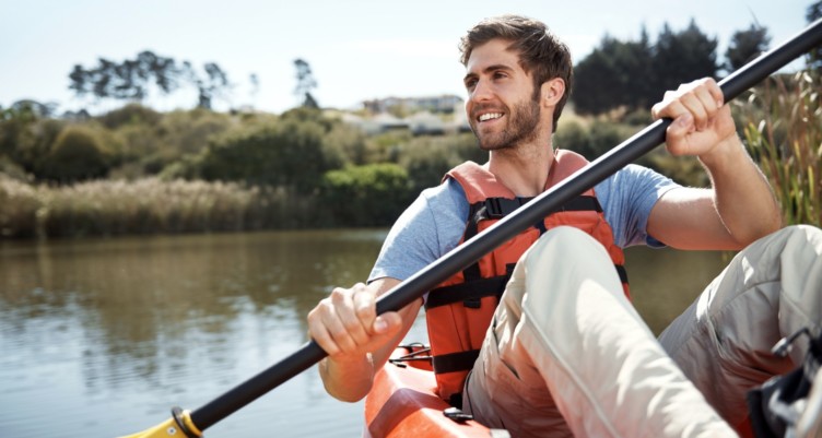 Man holding oar while kayaking on a lake.
