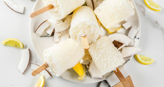 Dish of bulletproof lemon ginger coconut popsicles with ingredients scattered about