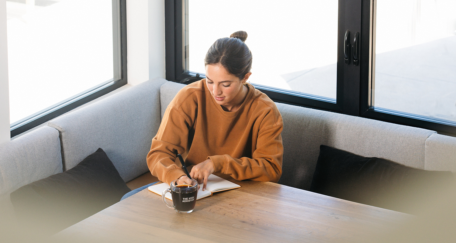 woman writing and drinking coffee