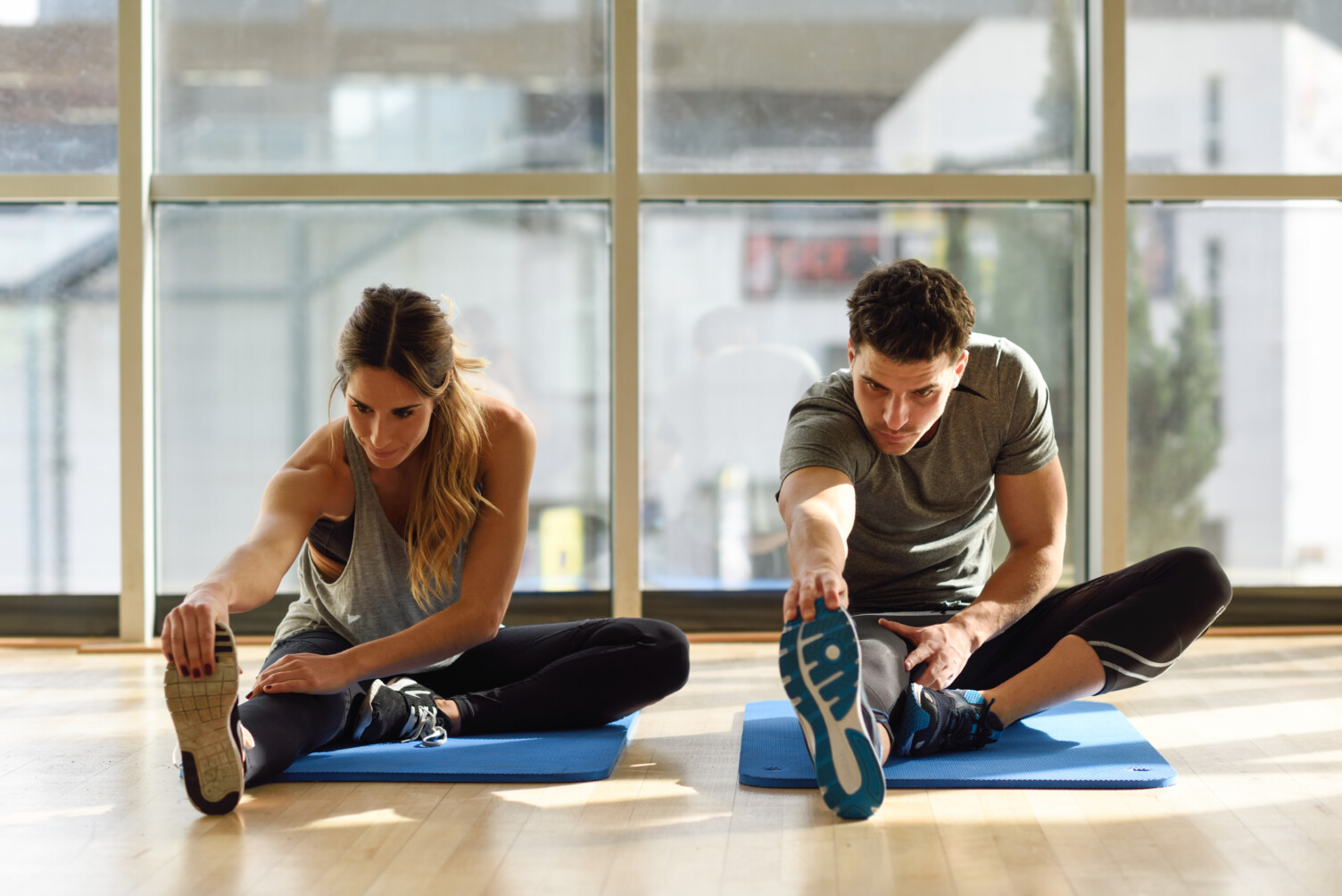 man and woman stretching in a workout studio